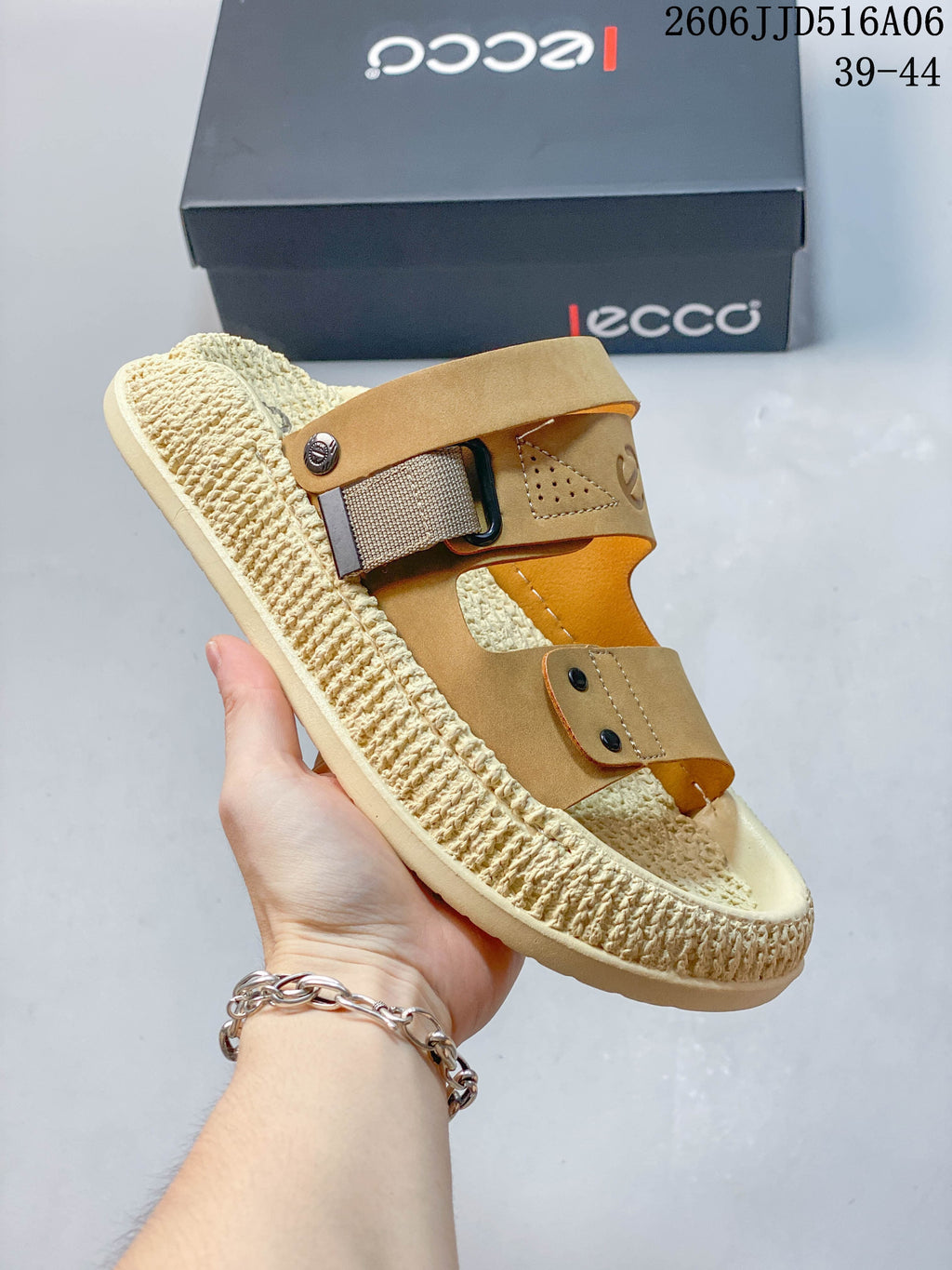 Angled view of a tan and cream sandal showing its adjustable strap hardware.