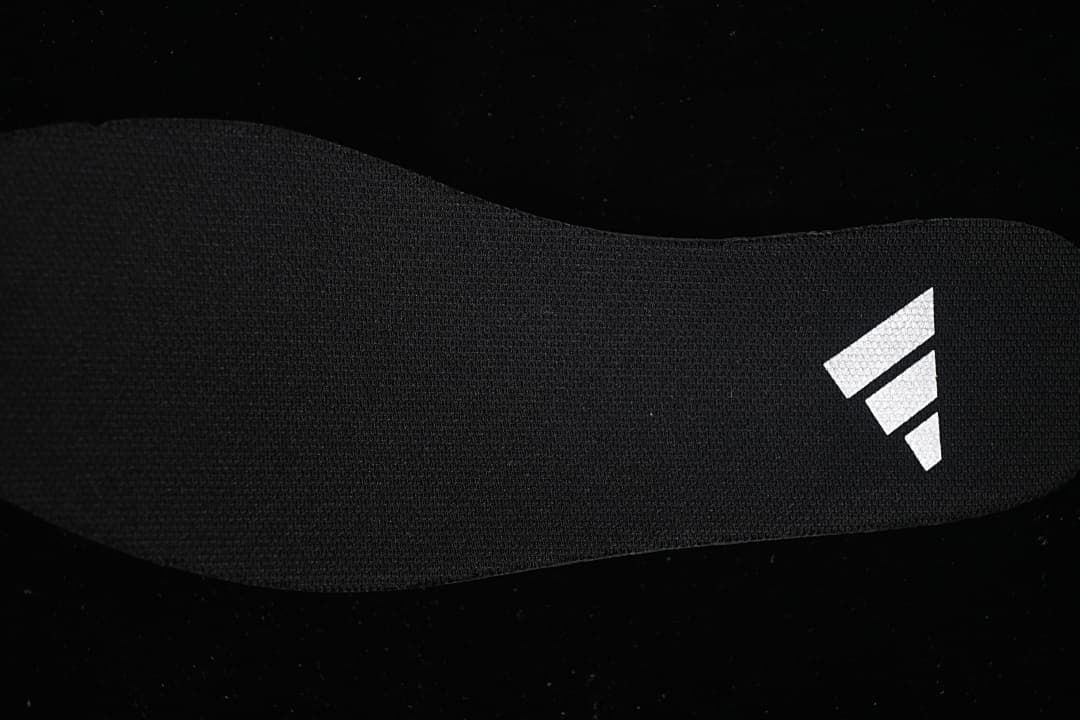 Close-up of a dark insole with a white logo mark