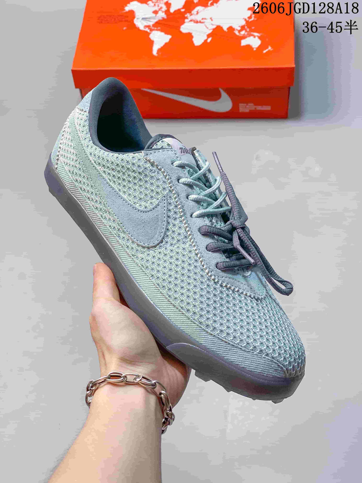 Close view of a gray-green Nike Astrograbber sneaker showing mesh-style panels, side Swoosh, and lace-up fastening.