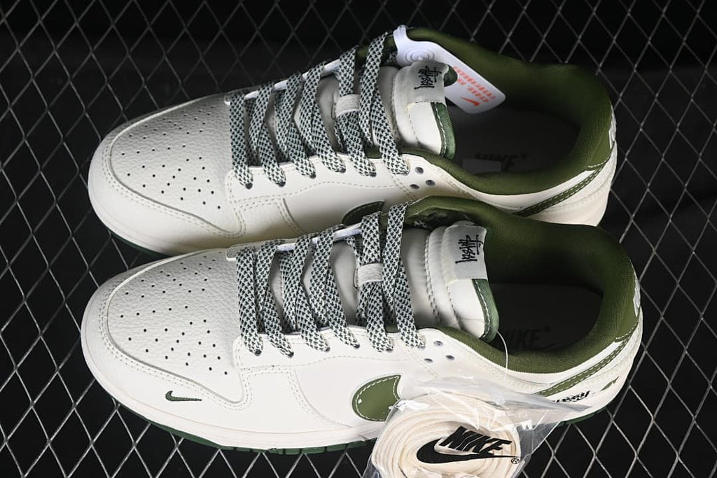 Pair of white and dark green low-top sneakers viewed from above, with patterned laces and an additional white lace set.