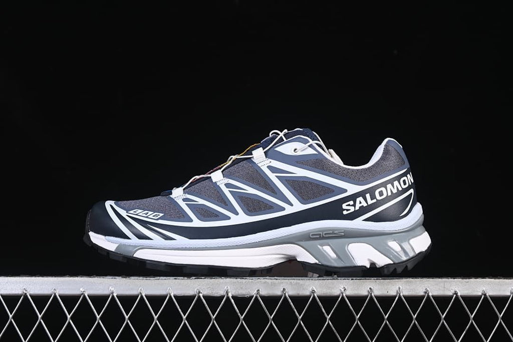 Side view of a gray, navy, and white Salomon XT-6 shoe.