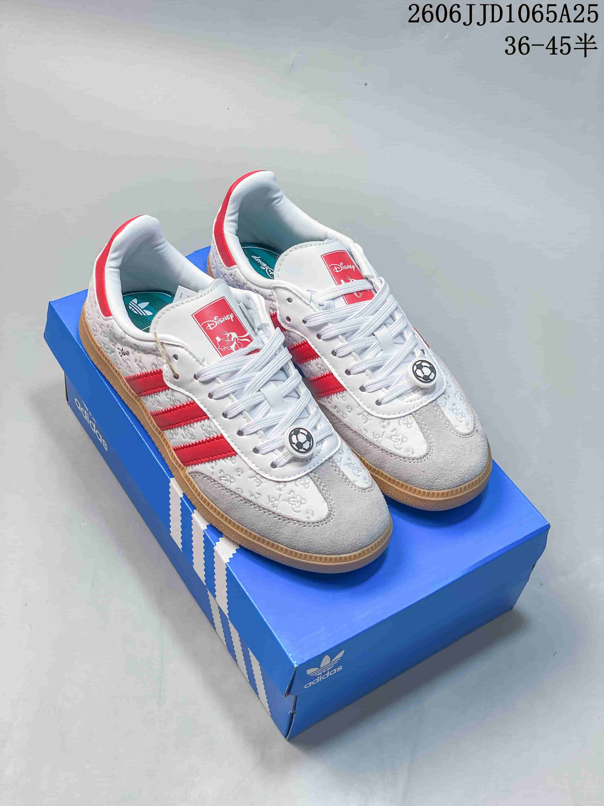 White low-top sneakers with red stripes, character-themed details, and gum-tone outsoles beside a blue shoebox