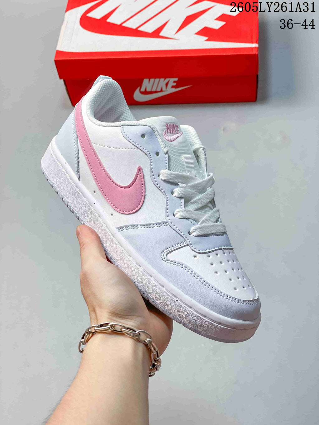 Angled side view of the white sneaker with pink Swoosh and heel accents