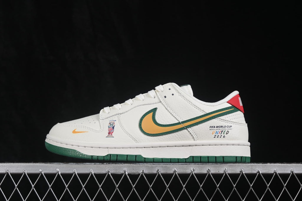 Side view of white Nike SB Dunk Low sneakers with a green-and-gold Swoosh, red heel detail, World Cup-themed side graphic, and green outsole.