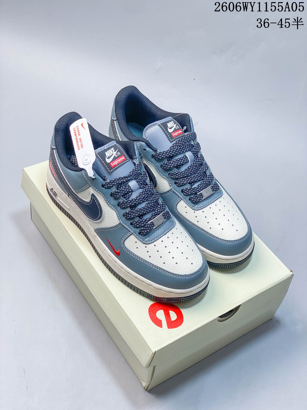 Pair of white and blue Nike Air Force 1 Low-style sneakers with dark laces and red accents, displayed on a box.