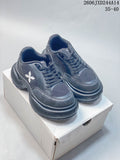 Pair of charcoal SMFK lace-up sneakers with white side emblems, shown from the front on a box.