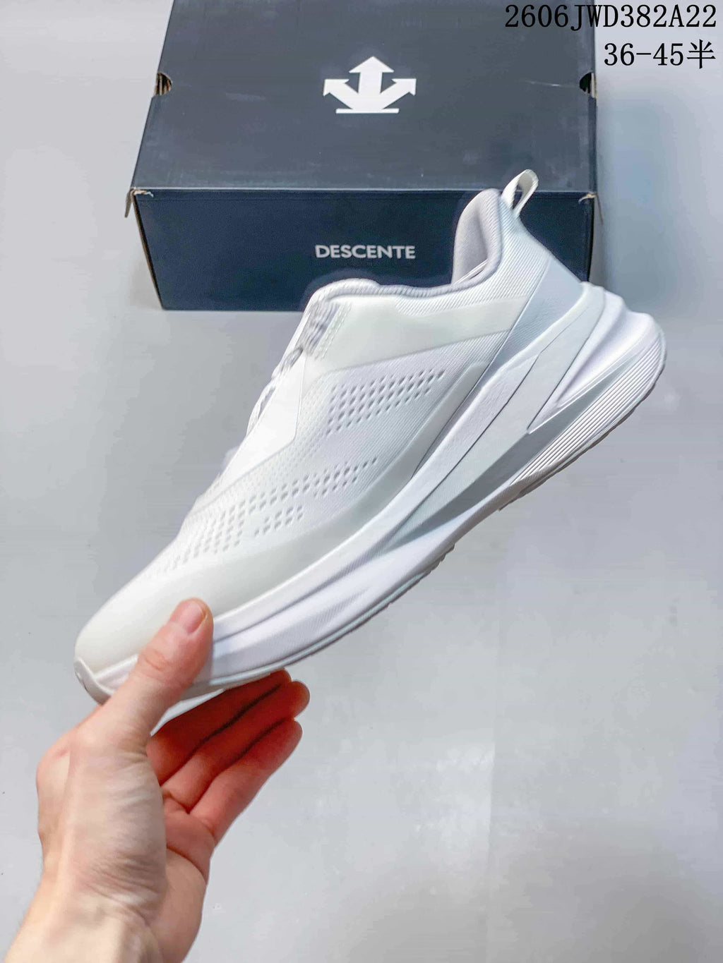 Side profile of the white DESCENTE running shoe with a sculpted midsole.