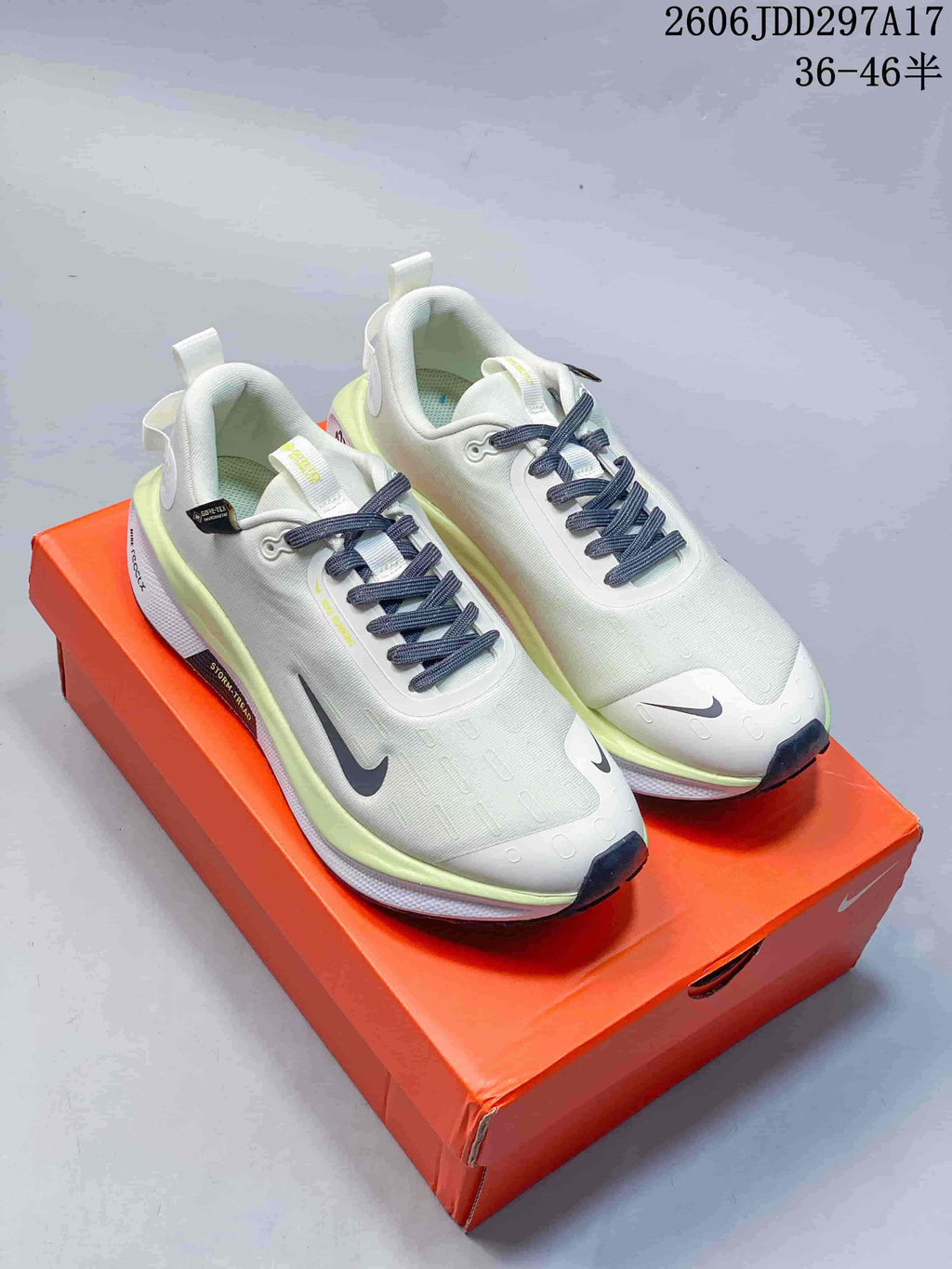 Pair of pale white Nike InfinityRN 4 shoes with lime accents and dark laces on an orange box
