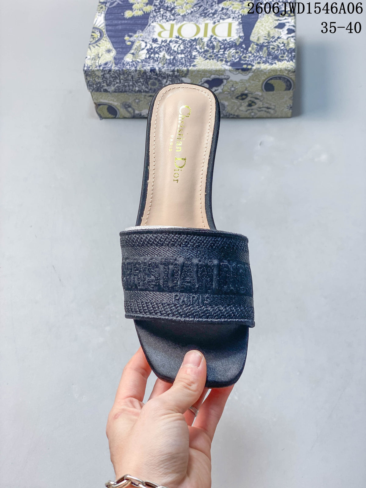 Front view of a dark navy mule sandal with a wide embroidered strap and square toe