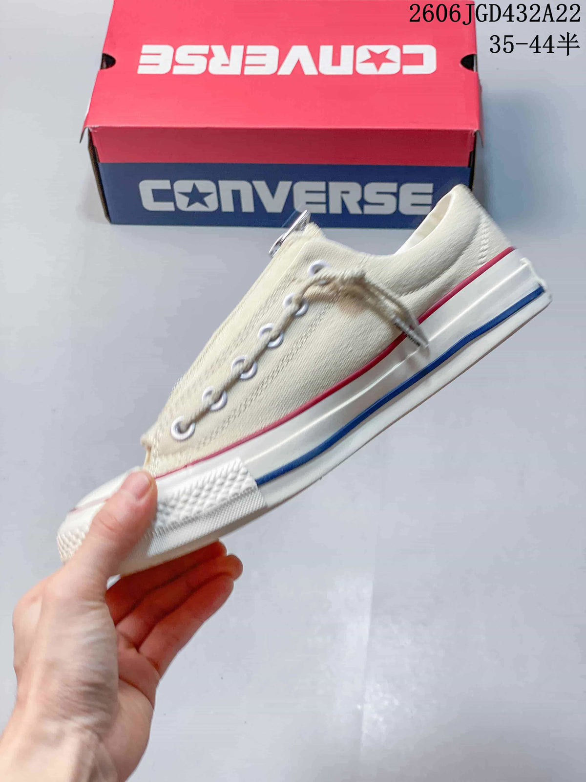 Side view of the cream low-top sneaker with red and blue sole accents