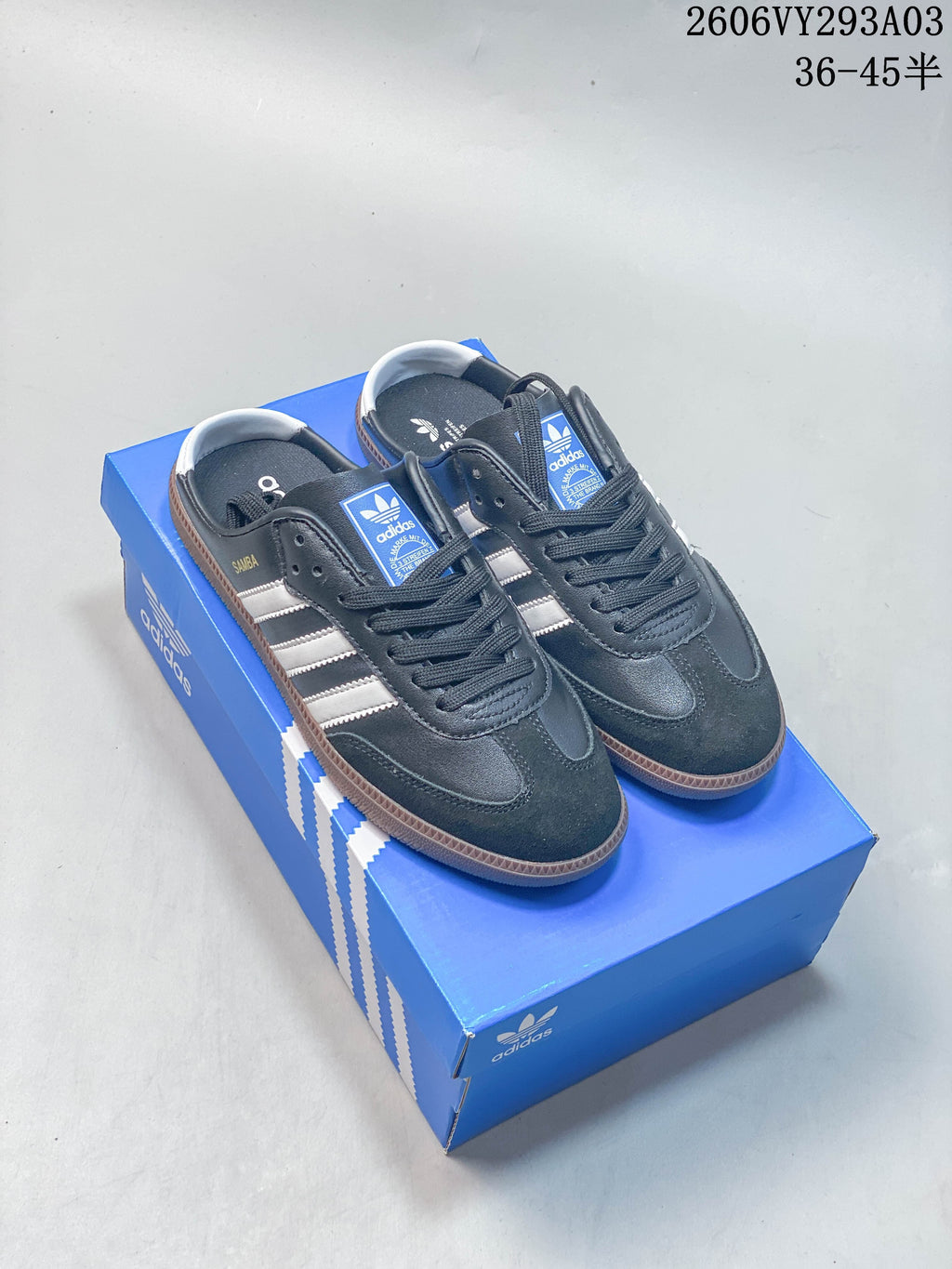 Navy Adidas low-top sneakers with white stripes and gum-colored soles on a blue shoe box.