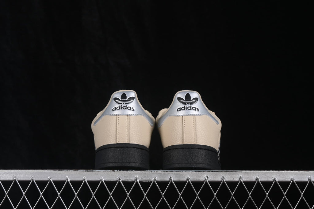 Rear view of the beige adidas Superstar II sneakers with silver heel panels, adidas branding, and black outsoles.