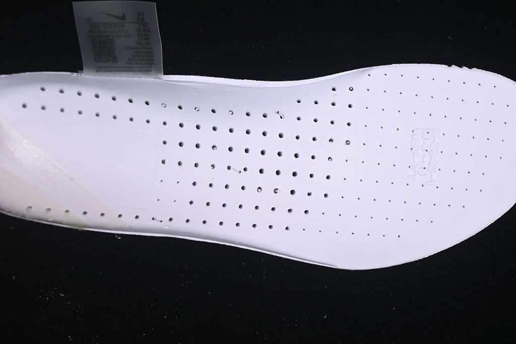 Close-up of the white shoe insole with perforations and a size label in the background