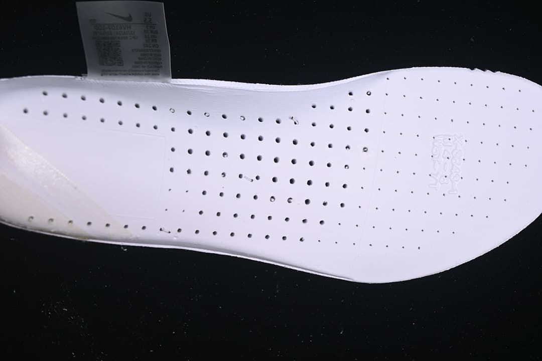 Close-up of the white shoe insole with perforations and a size label in the background