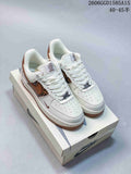White low-top sneakers with brown patterned side panels, brown accents, perforated toe panels, and decorative lace charms.