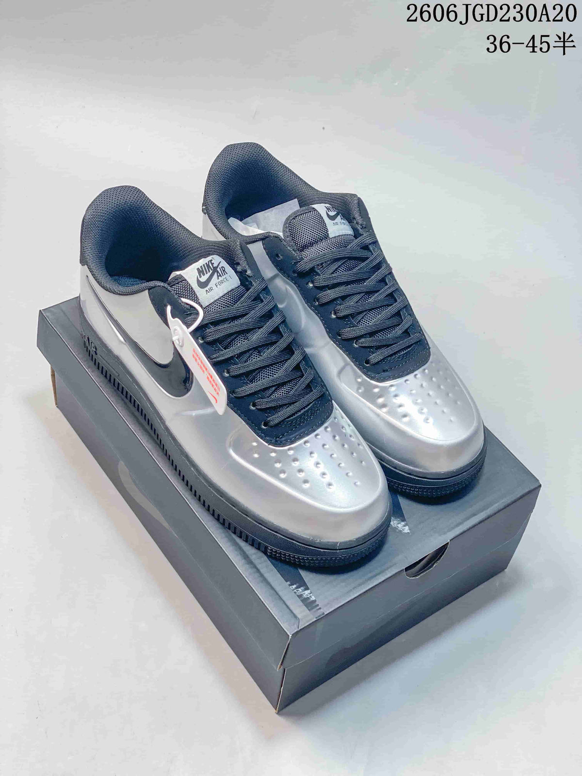 Silver and dark navy low-top sneakers displayed on a shoe box