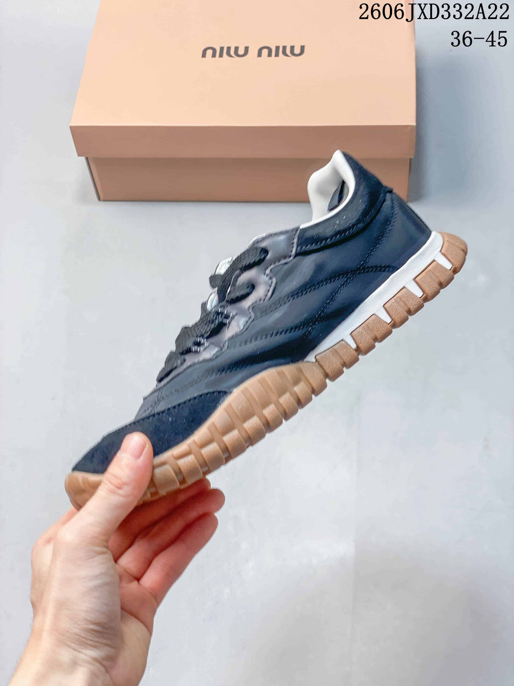 Side profile of a gray and navy low-top sneaker with a tan-colored textured outsole.