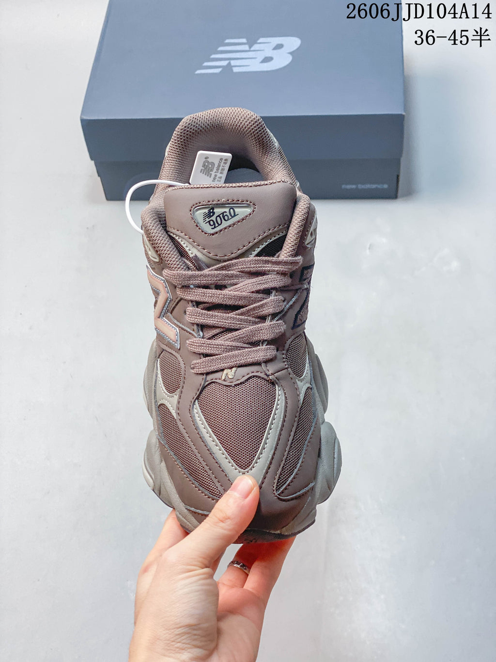 Front view of a mauve and grey New Balance 9060 sneaker showing its mesh panels and laces.