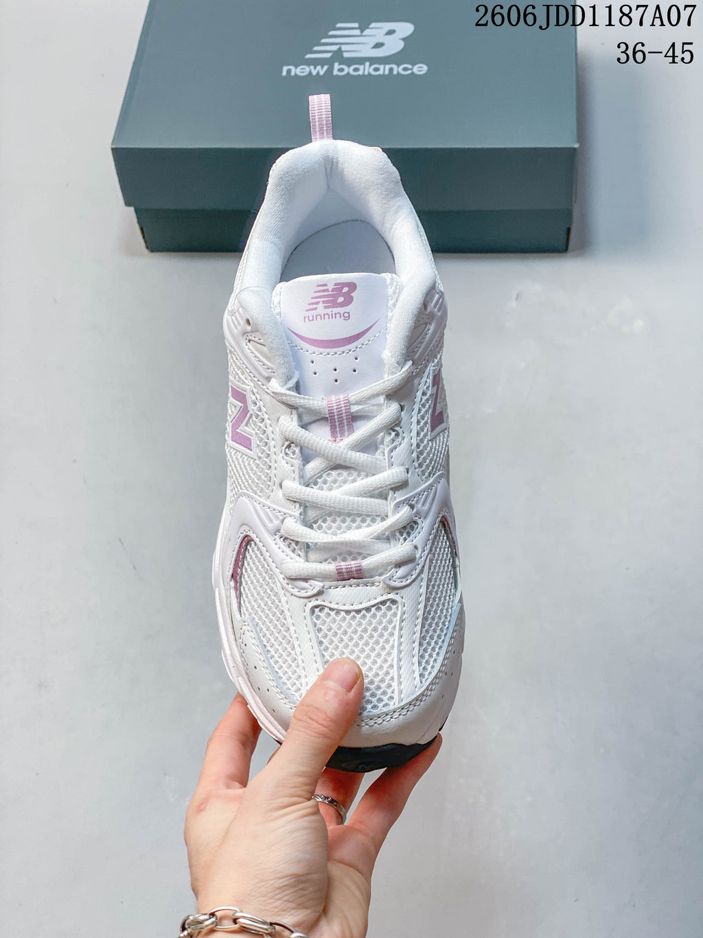 Front view of a white and pink New Balance mesh sneaker