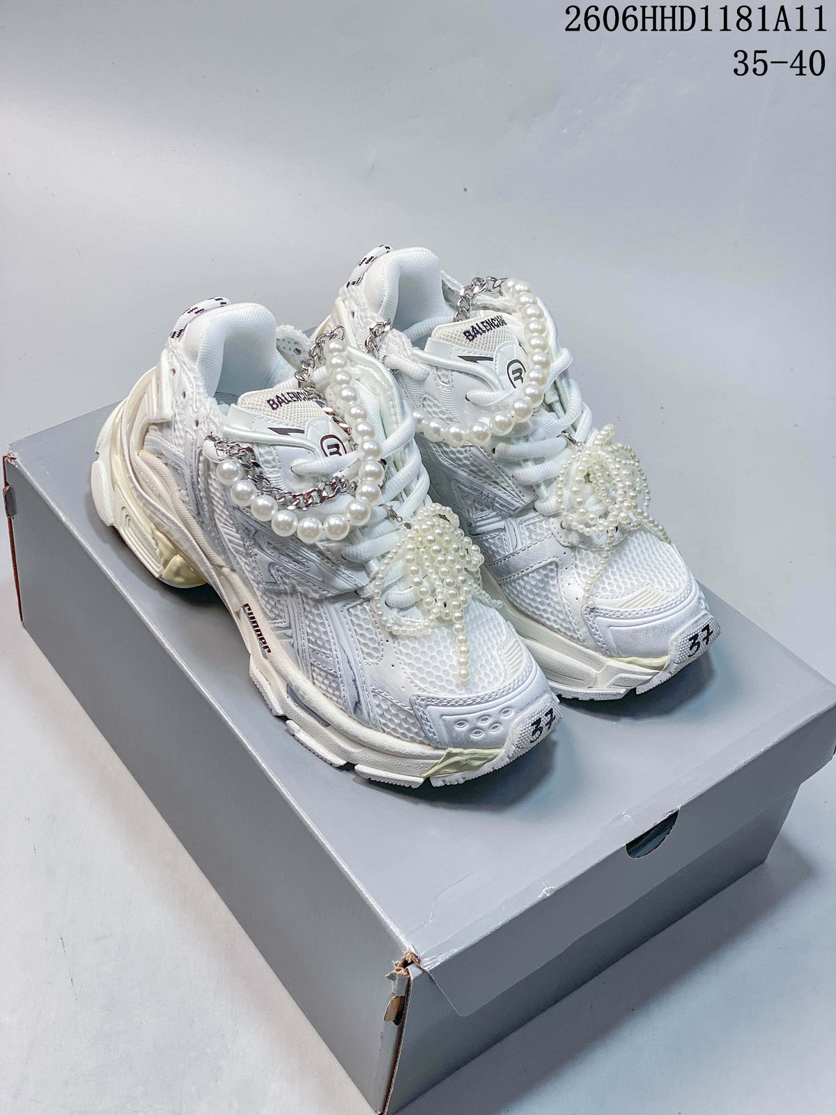 Pair of white Balenciaga Runner Gradient sneakers with pearl-look and chain lace embellishments, shown on a box.