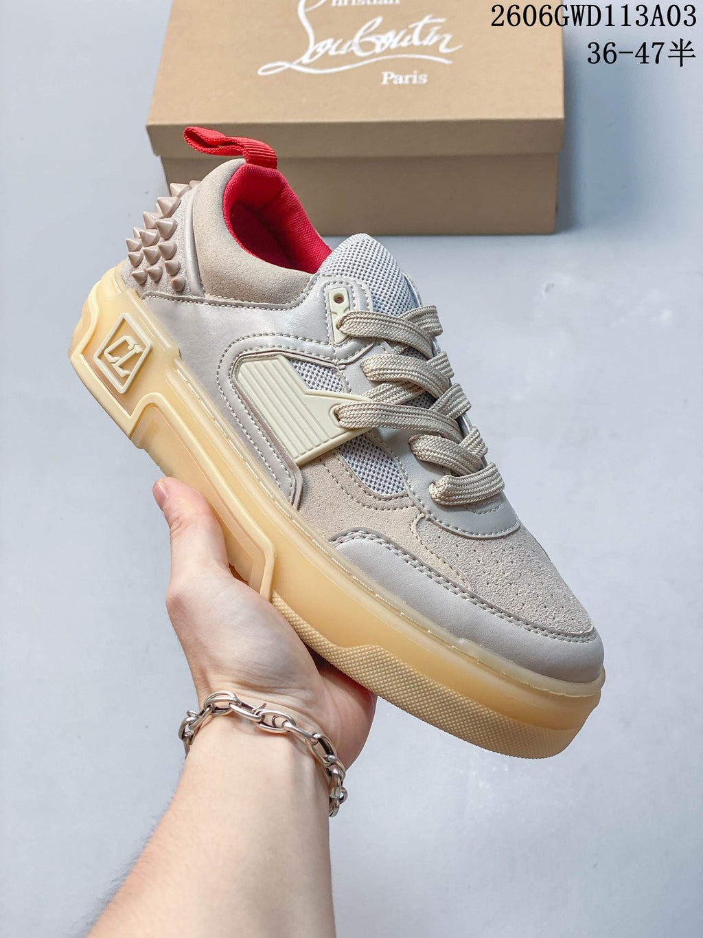 Angled side view of a sneaker showing its layered upper, heel studs, and thick sole