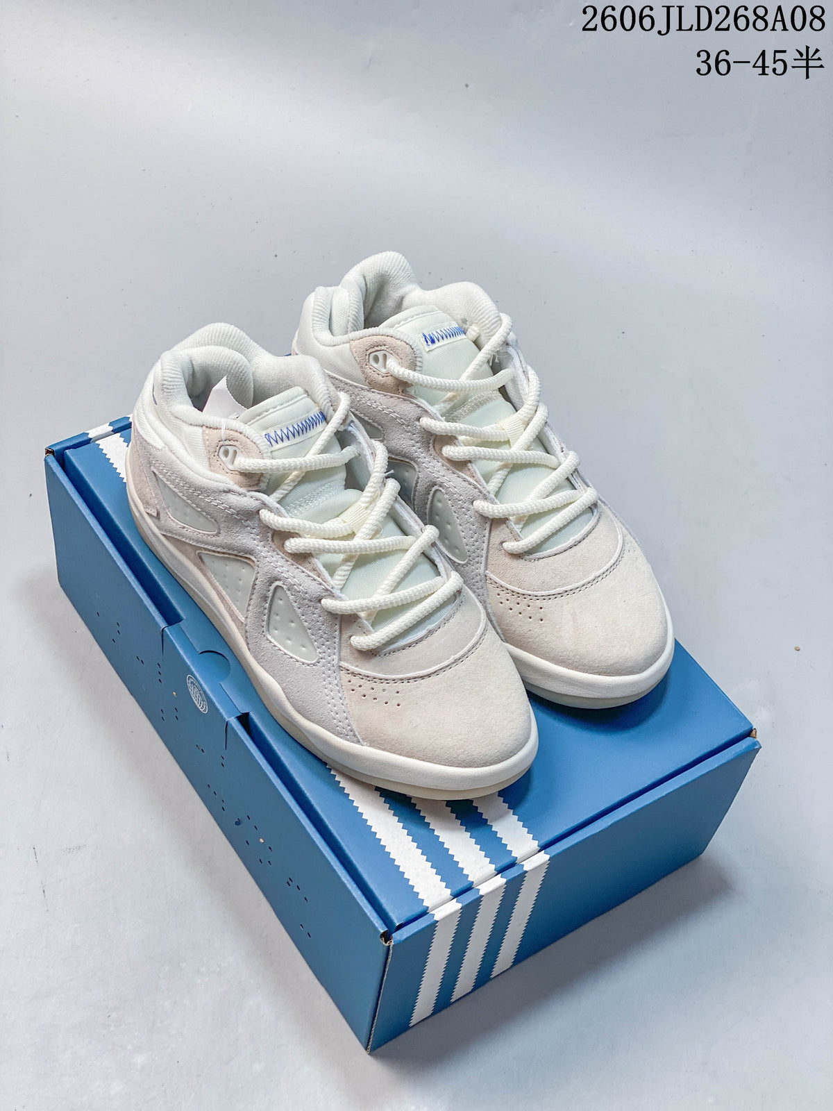 Pair of cream and off-white adidas Bad Bunny Badbo 1.0 sneakers on a blue box