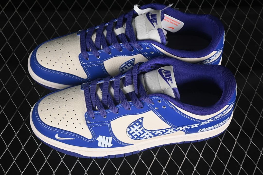 Top view of a pair of blue and off-white Nike SB Dunk Low sneakers with patterned Swooshes and blue laces.