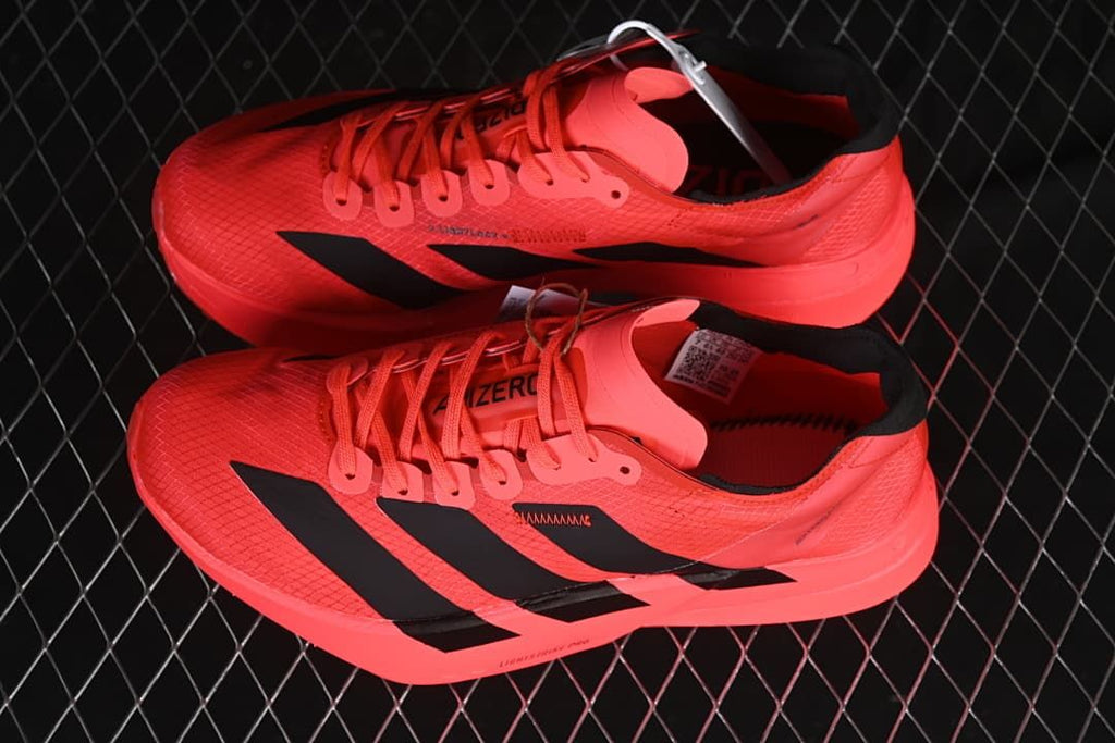 Pair of coral Adidas Adizero running shoes with black stripes