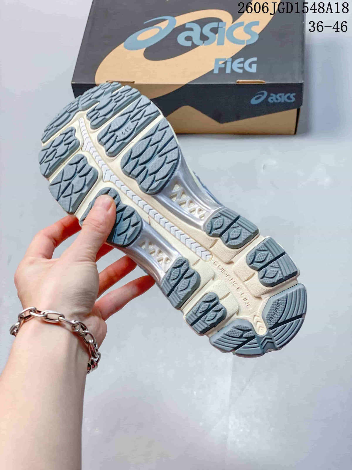 Close view of the segmented outsole on a silver and turquoise running shoe.