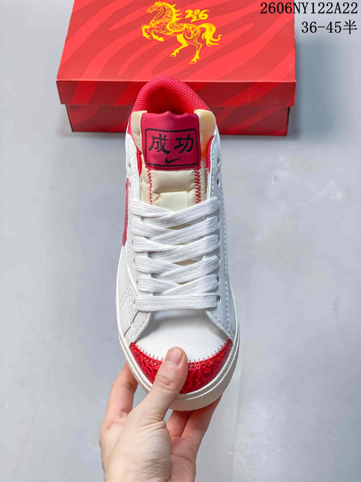 Top view of the sneaker showing white laces, padded tongue, and red patterned toe overlay.