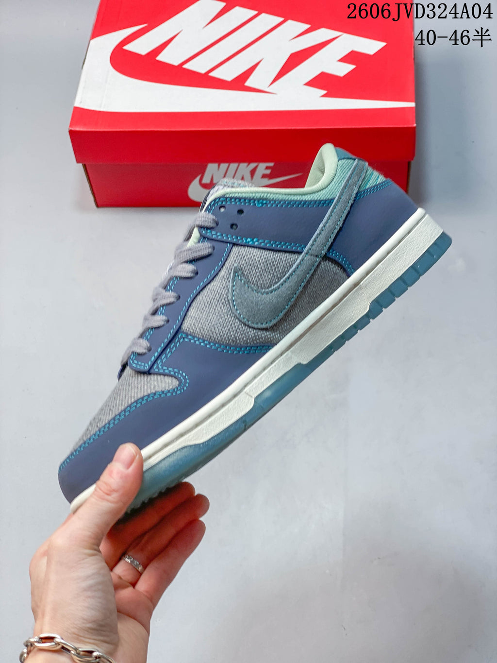 Side profile of a gray and blue Nike Dunk Retro SE sneaker showing its stitched panels