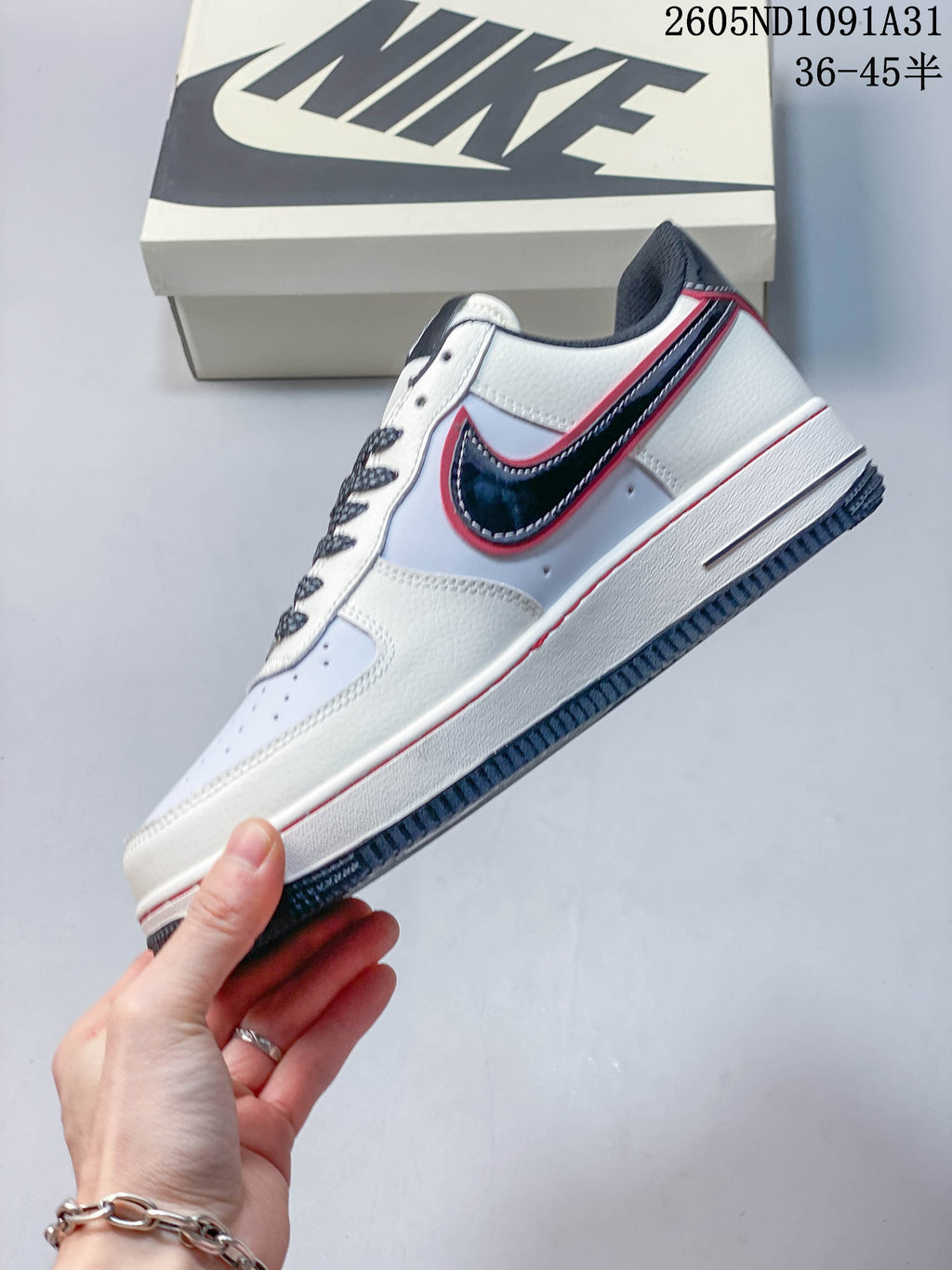Side view of the white sneaker with navy and red accents.