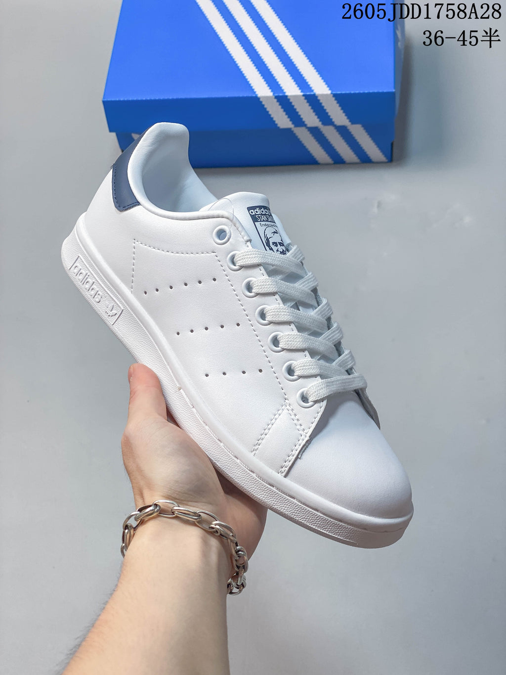 Angled side view of a white low-top sneaker with perforated panels and a dark blue heel tab.