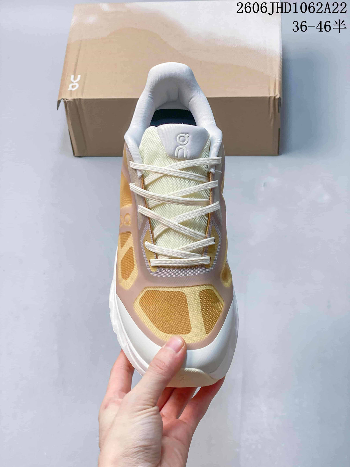 Front view of an On Cloudtilt Remix sneaker with cream laces and gold-toned panels.