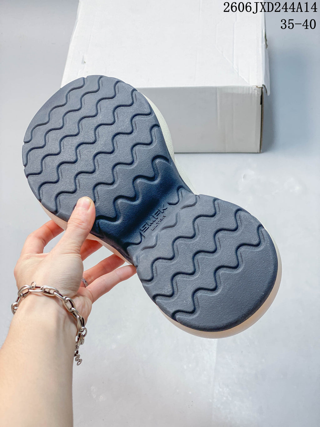 Underside of the sneaker showing a dark outsole with a wavy tread pattern; image overlay shows code 2606JXD244A14 and sizes 35–40.