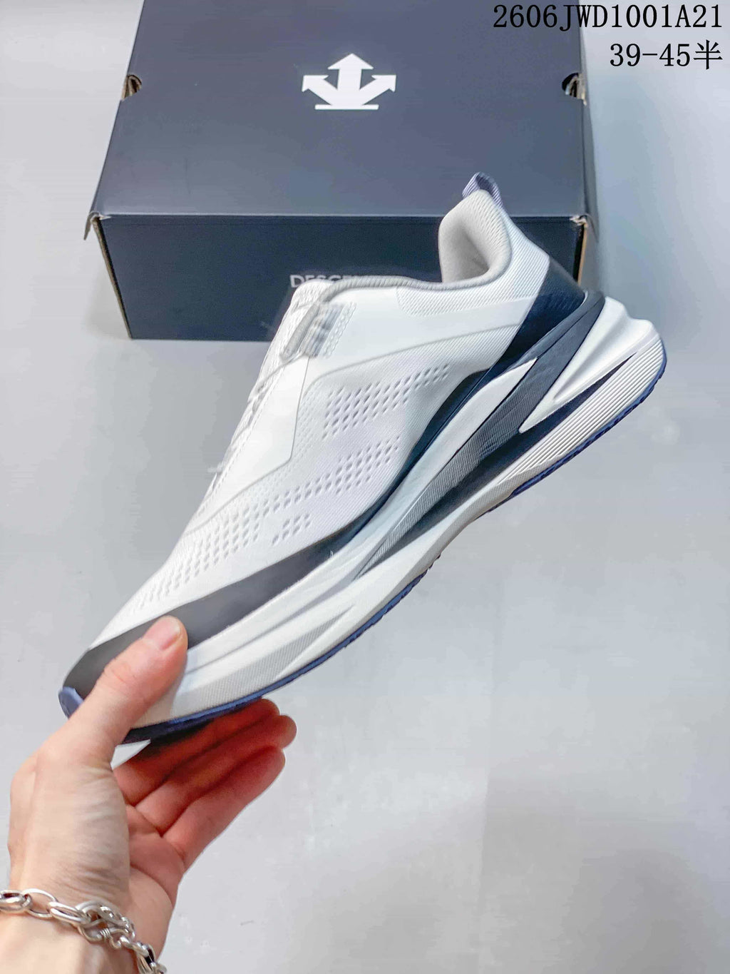 Side view of a white DESCENTE sneaker with dark gray and blue-violet detailing