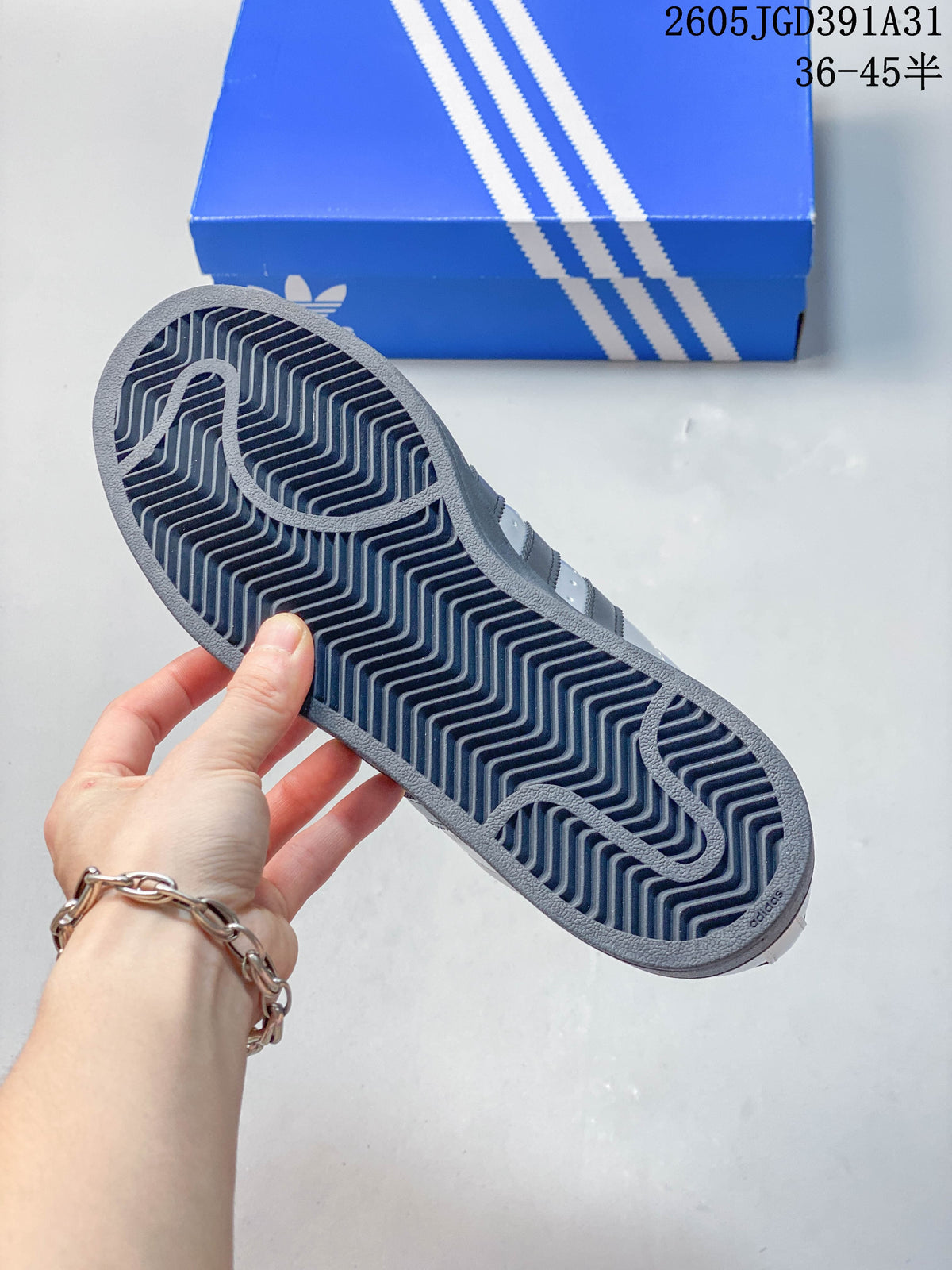 View of the dark patterned outsole on a silver Superstar sneaker.