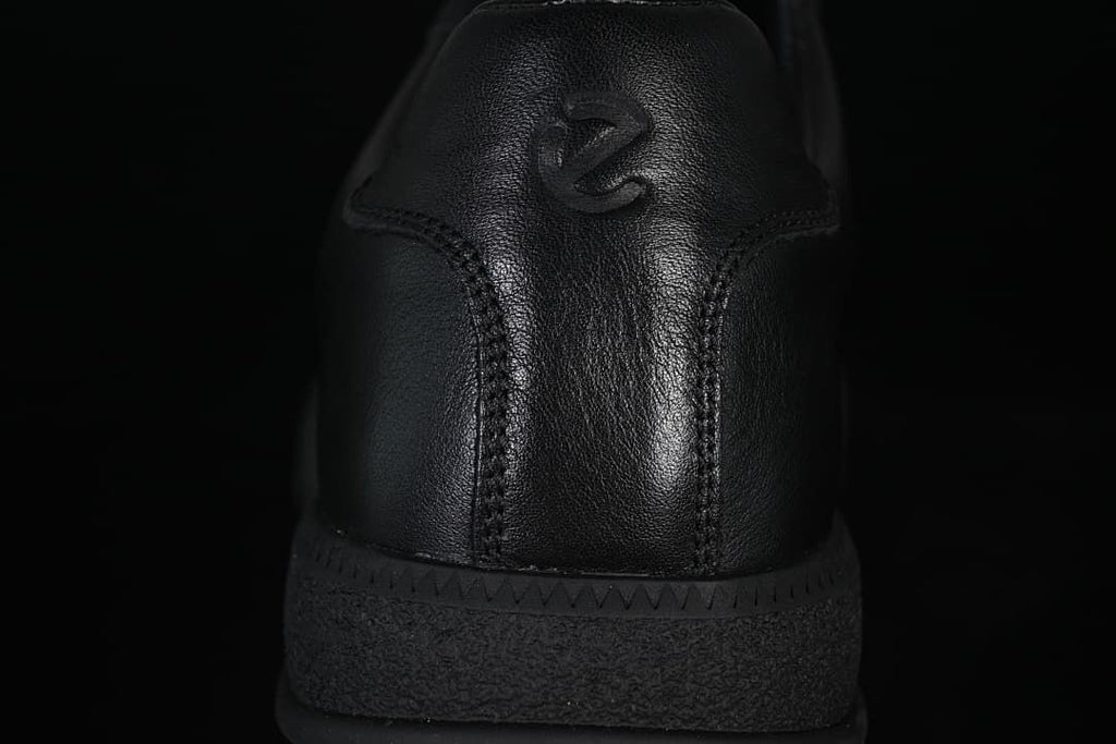 Rear close-up of the black sneaker with embossed heel logo