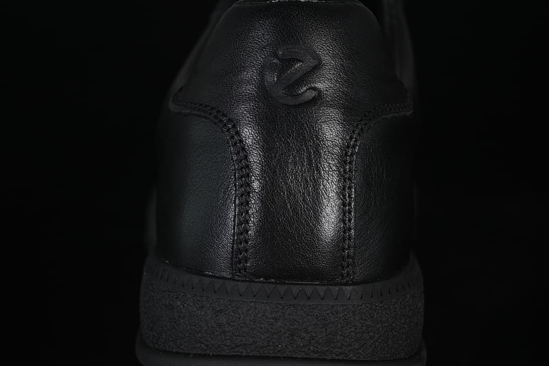 Rear close-up of the black sneaker with embossed heel logo