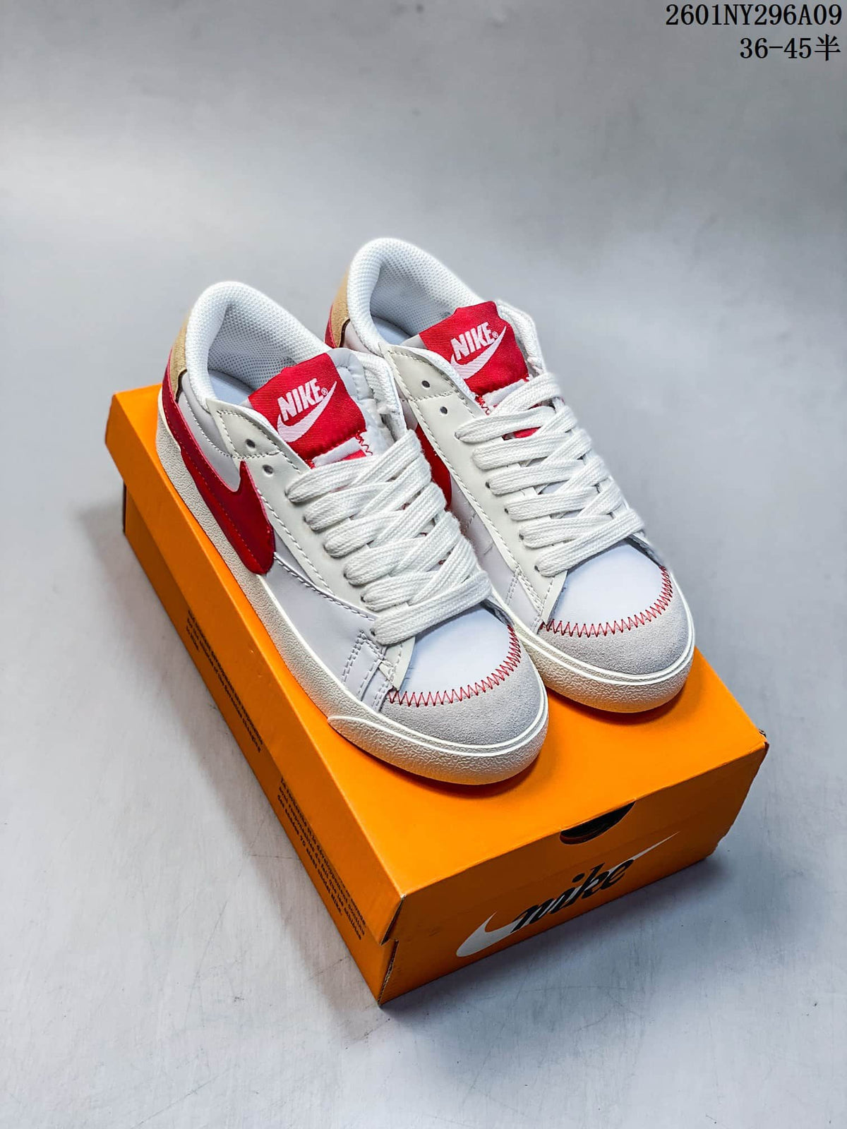 Pair of white and red Nike Blazer Low '77 Jumbo sneakers shown on an orange shoe box.