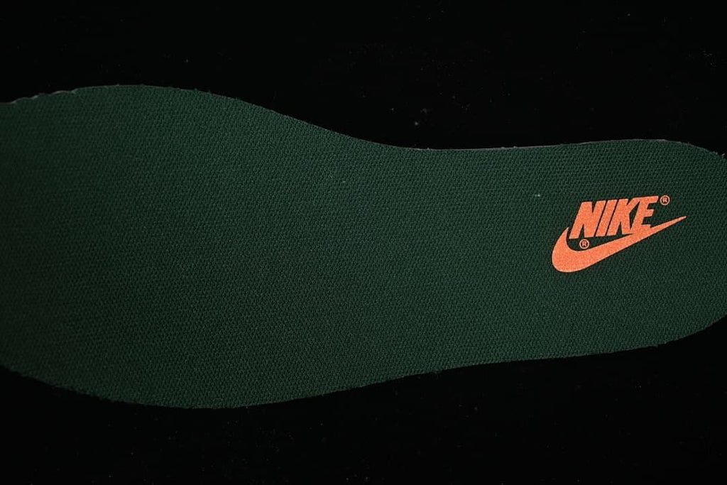 Close-up of a dark green shoe insole with an orange Nike logo