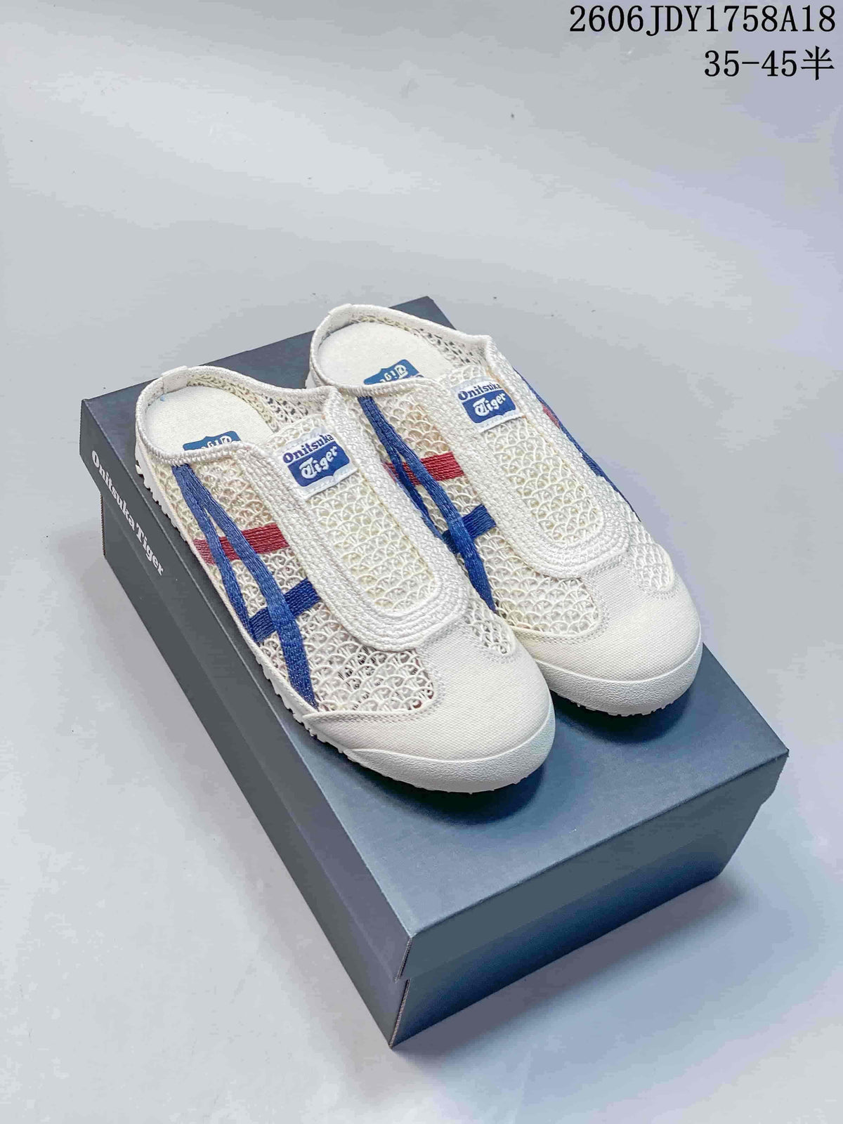 Pair of ivory Onitsuka Tiger Mexico 66 Sabot slip-on sneakers with blue and red side stripes, shown on a shoe box