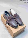 Pair of brown pebbled-finish slip-on loafers with metal bit detail, shown on a box