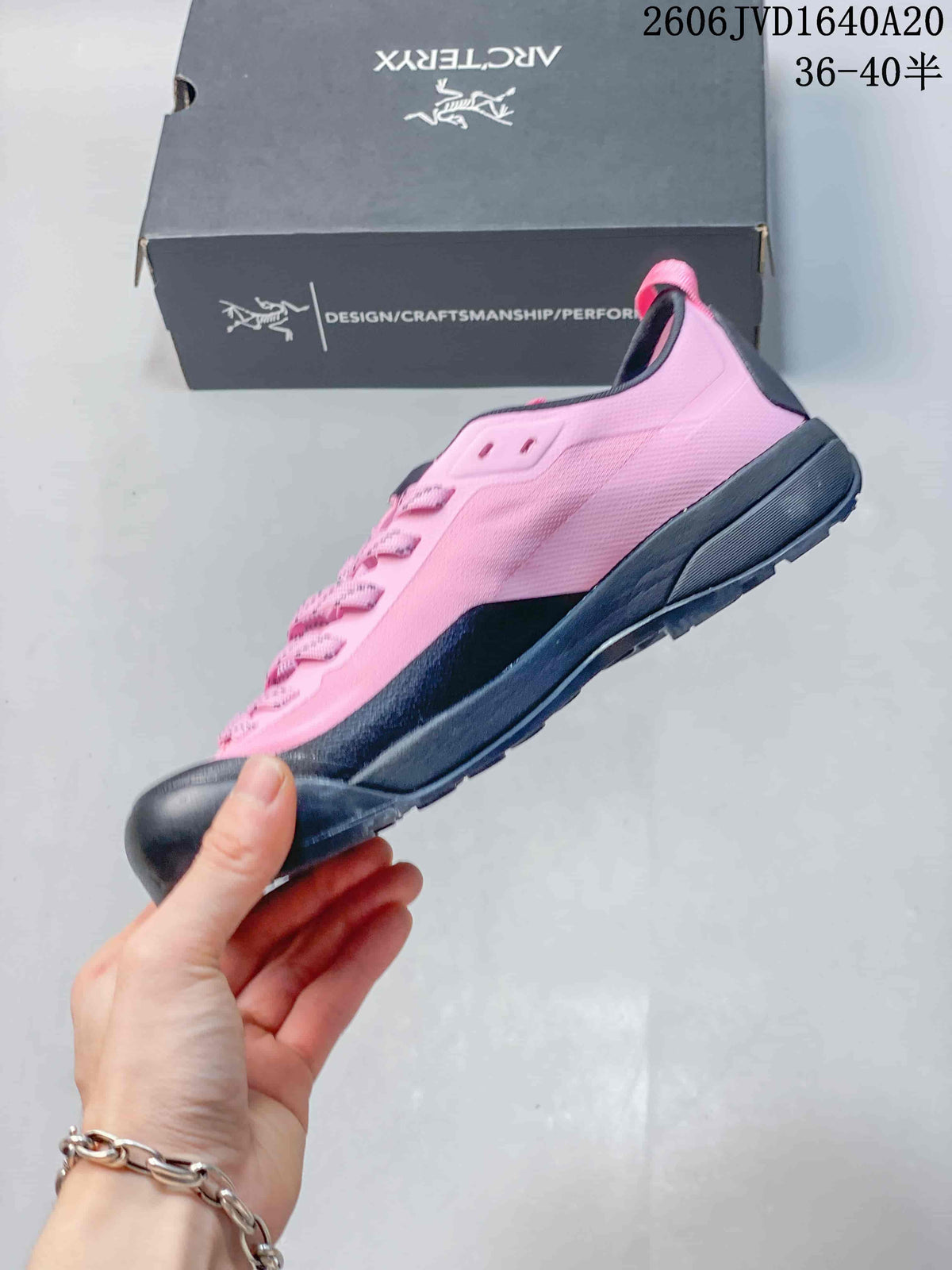 Side view of a pink low-cut trail shoe with dark gray trim