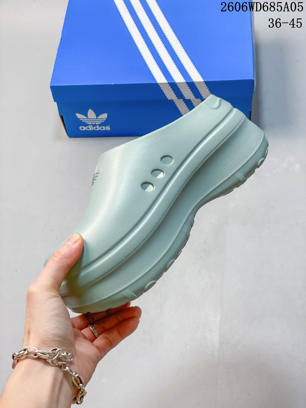 Side view of a light blue mule shoe with three perforations and a raised sole