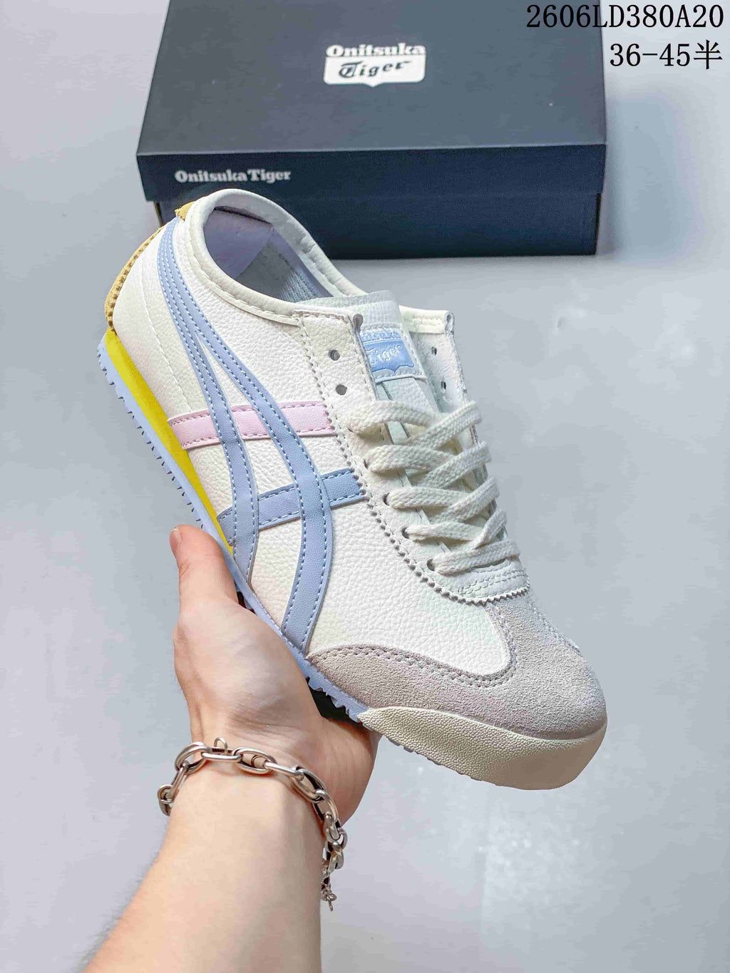 Side view of a white low-top sneaker with pastel blue and pink side stripes.