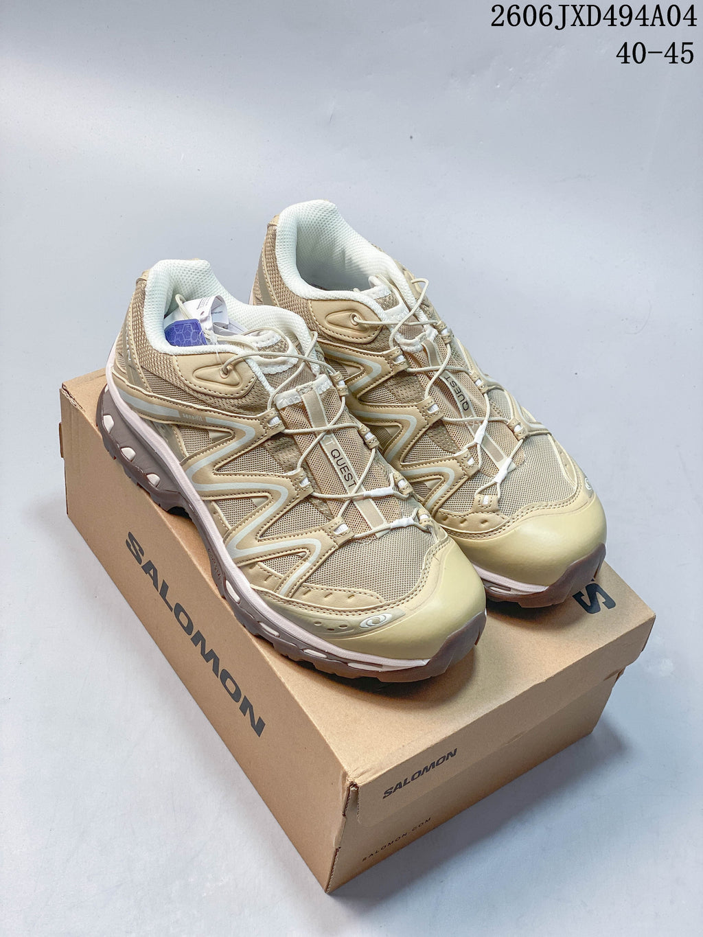 Sand-colored Salomon XA Pro 3D sneakers displayed on a branded shoe box.