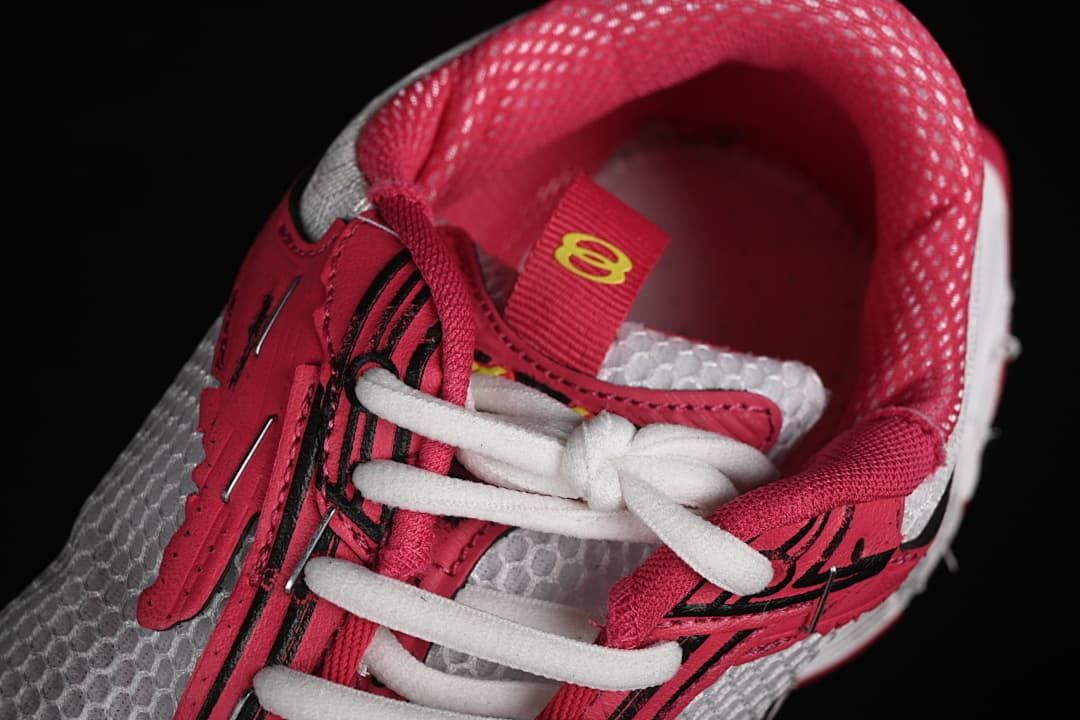 Top-down close-up of white laces, pink overlays, and mesh panels