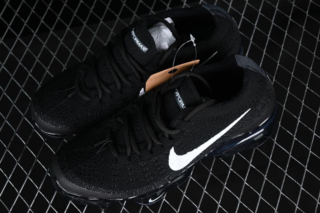 Pair of black sneakers with white Swooshes shown from above.