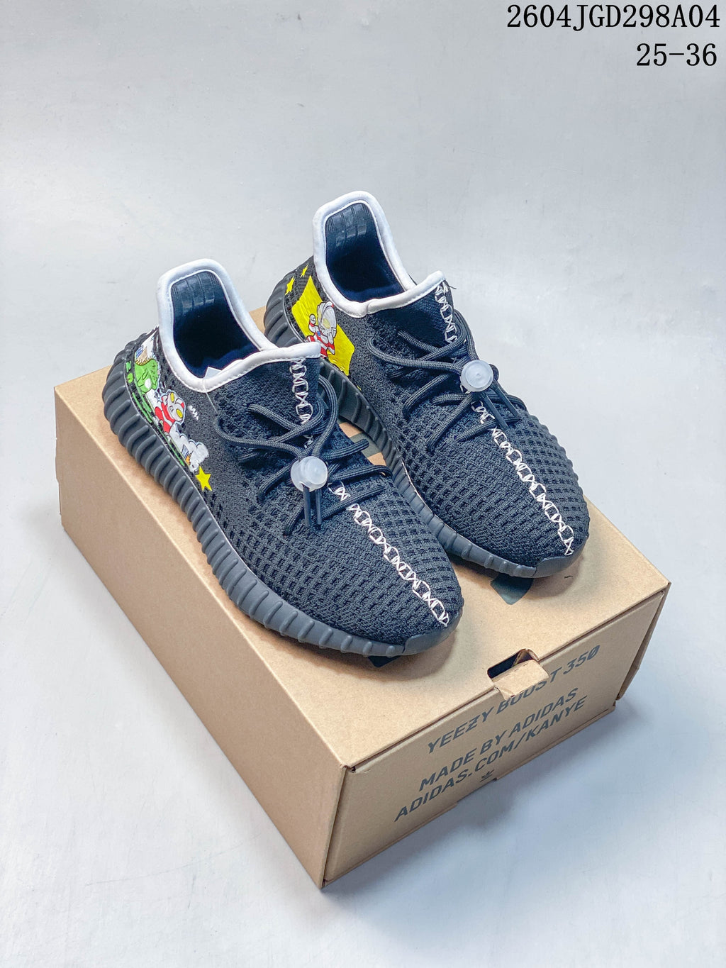 Pair of charcoal kids’ sneakers with colorful cartoon side graphics on a box